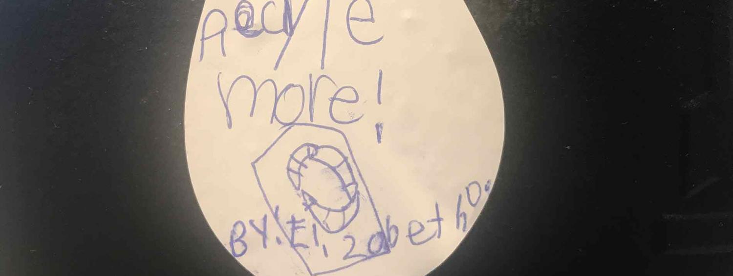 A photo of an oil droplet. It reads 'recycle more!' in a child's handwriting, and is signed from Elizabeth. 